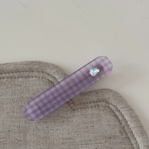 Détail de la pince à cheveux à carreaux lavande avec un diamant en forme de cœur brillant