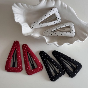 Detailed view of six fabric polka dot triangular BB hair clips on a white ceramic dish