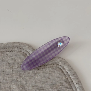 Gros plan sur une barrette à carreaux violets avec cristal en cœur et texture translucide