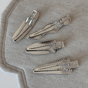 Detailansicht von vier silbernen Metall-Haarspangen mit konzentrischen Wellenmustern