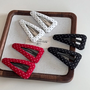 Close-up of six geometric triangle snap clips with polka dot fabric in red, black and white