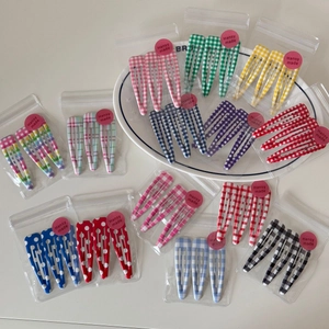 Detail of colorful plaid and polka dot metal BB hair clips in branded packaging