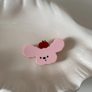 Gros plan d'une pince à cheveux ours rose avec détail de pomme sur plateau