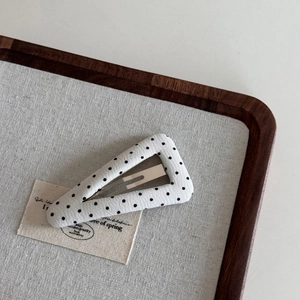 Polka dot fabric triangle hair clip on a vintage wooden tray with a linen liner