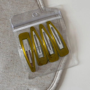 Set of four olive green resin triangle snap hair clips in clear retail packaging