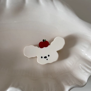 Détail d'une pince à cheveux nuage blanc avec décor pomme sur plateau céramique