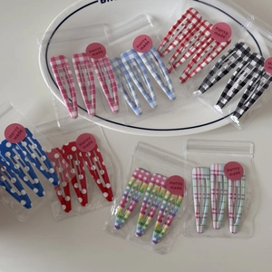 Detail shot of assorted plaid and polka dot hair clips in clear packaging on a tray