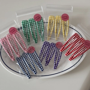 Close-up of three-piece BB hair clips featuring colorful plaid patterns in a ceramic plate