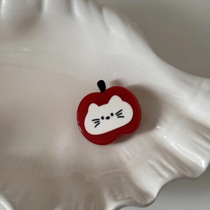 Gros plan d'une pince à cheveux pomme rouge avec chat mignon sur assiette coquille