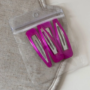Detail view of three translucent pink triangular BB hair clips in clear polybag packaging