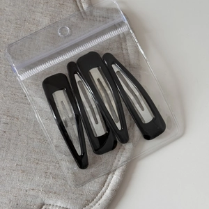 Detailed view of four black metal BB hair clips in teardrop and rectangular shapes