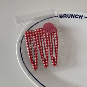 Close-up of three red and white checkered BB hair clips in transparent Hansy made packaging