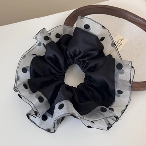 Macro detail of large black polka dot organza scrunchie with elegant tulle ruffle edging