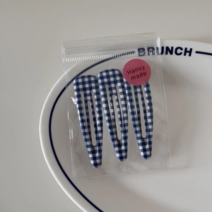 Detail view of three blue plaid BB hair clips on a white ceramic plate for girls