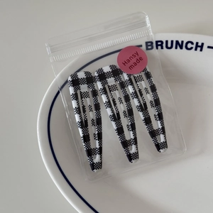 Close-up of 3-piece checkerboard pattern BB hair clips in minimalist transparent packaging
