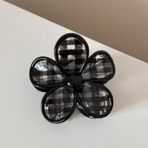 Détail de la pince à cheveux en fleur avec motif à carreaux noir et blanc pied-de-poule