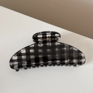 Détail d'une pince à cheveux à damier noir et blanc avec ressort en métal doré