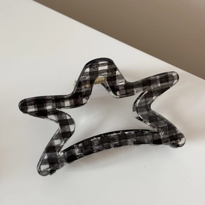 Vue détaillée de la pince à cheveux en étoile avec motif vichy noir et blanc et ressort doré
