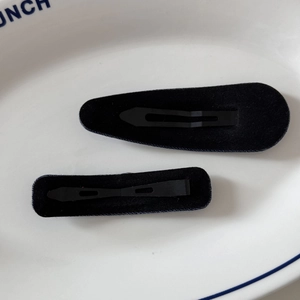 Vue détaillée d'un ensemble de pinces à cheveux floquées noires sur une assiette en céramique
