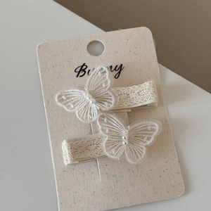 Detailed macro view of off-white lace bow hair clips with pearls and embroidery