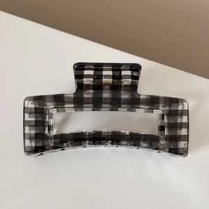 Détail d'une pince à cheveux à motif vichy noir et blanc avec ressort métallique doré