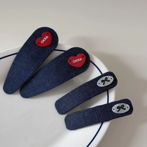 Détail du lot de barrettes en denim bleu marine avec cœur rouge et nœud sur assiette blanche