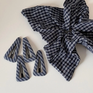 Close-up of navy blue checkered hair scrunchie and four matching striped triangle hair clips