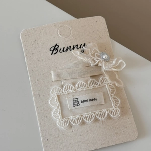 Detail view of lace bow hair clips with pearls and hand made label on display card