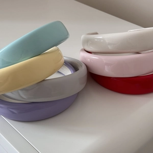 Detailed pile of glossy candy-colored sponge headbands with soft fabric lining in seven colors