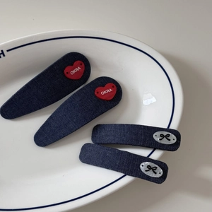 Détail de quatre barrettes en denim avec cœurs rouges et nœuds sur une assiette blanche