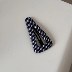 Detailed view of navy blue striped fabric covering the triangular metal hair clip