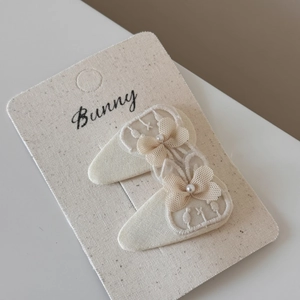 Detail of cream lace bow hair clips with faux pearl accents on display card