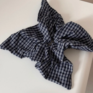 Close-up of oversized black and white checkered scrunchie with soft pleated texture