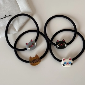 Detailed set of four cat-shaped hair ties in grey, black, tortoiseshell, and white acrylic