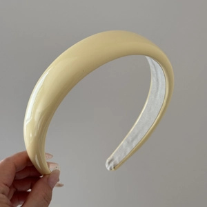 Detail view of a glossy pale yellow padded headband with non-slip fabric inner lining