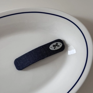Détail de la pince à cheveux en denim bleu marine avec un joli motif de nœud blanc