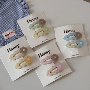 Close-up of pastel flower and checkered hair clips set on branding card display