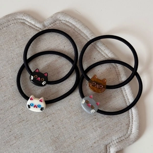 Detailed set of four elastic cat hair ties in black, amber brown, white, and grey colors