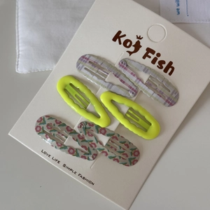 Close-up of six wavy printed BB hair clips in purple plaid, green, and floral patterns
