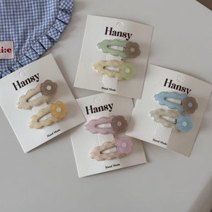 Close-up of pastel flower hair clips in mint green and cream yellow with wave edges