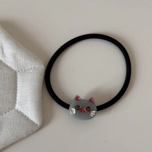 Detailed close-up of a high-elastic black hair tie featuring a cute grey resin cat head charm