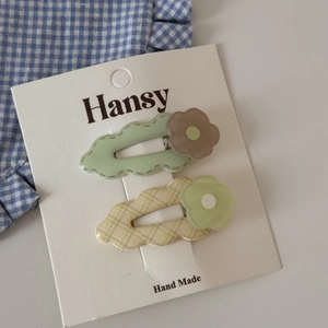 Detail of colorful matte flower hair clips with plaid patterns on a display card