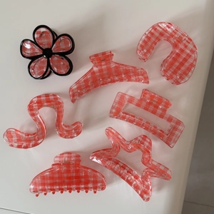 Detail view of 7-piece red plaid hair claw set in various geometric and floral shapes