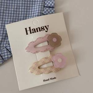 Detail shot of two cute cloud-shaped hair clips with floral patterns on a display card