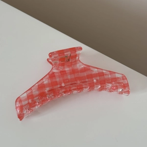 Detailed view of large red and white checkered hair claw clip with transparent resin finish