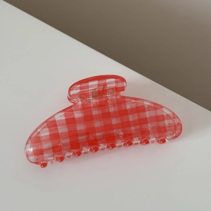 Detail of red and white checkered claw clip showing transparent texture and metal spring