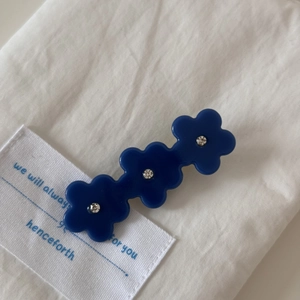 Détail de la pince à cheveux fleurie bleu marine avec strass blancs sur tissu doux