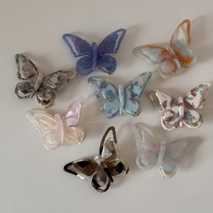 Detailed top view of eight colorful acetate butterfly hair clips with marble texture