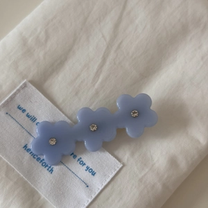 Gros plan sur la barrette fleurs en acétate avec cristaux sur tissu en coton blanc