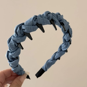 Close-up of braided denim headband showing unique black toothed comb and blue fabric texture
